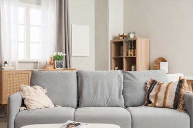 Modern oturma odasının iç kısmında şık minderleri olan gri kanepe.