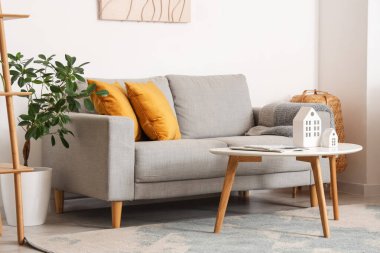 Gri kanepeli, kahve masalı ve çiçekli şık bir oturma odası.