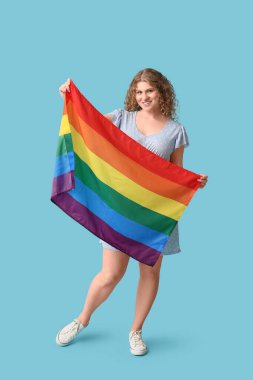 Beautiful young woman with LGBT flag on blue background