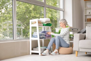 Güzel genç bir kadın, evde kıyafetlerini düzenliyor.