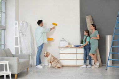 Yeni evlerinin tamiri sırasında aile duvarlarını boyayan hamile bir kadın.