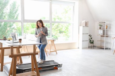 Ofisteki koşu bandında su eğitimi almış güzel bir iş kadını.