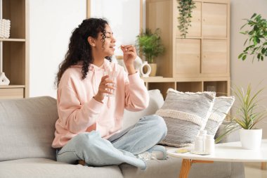 Genç Afro-Amerikalı kadın evde balık yağı alıyor.