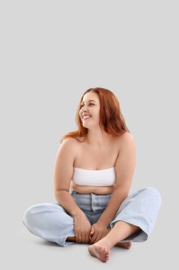 Güzel ve iri yarı bir kadın arka planda oturuyor.