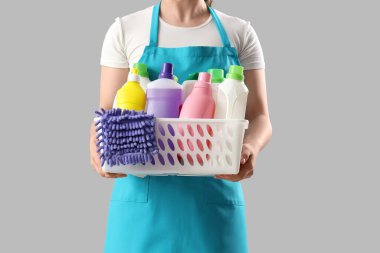Arka planda temizlik malzemesi sepeti olan kadın hademe, yakın plan.