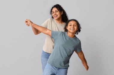 Gri arka planda kızı olan güzel, mutlu, Afro-Amerikan bir anne.