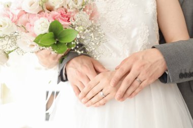 Yeni evliler, yüzükleri ve çiçekleriyle düğün günlerinde birbirlerine sarılıyorlar.