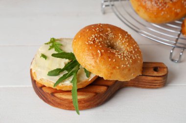 Beyaz ahşap masada tereyağı ve roka ile lezzetli simit panosu.