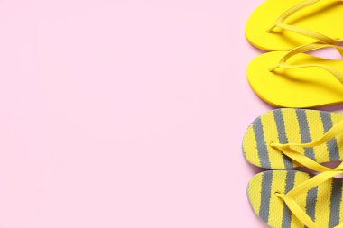 Pembe arka planda farklı plaj terlikleri.