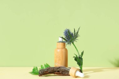 Gerekli yağ şişesi, ağaç kabuğu ve çiçek renginde kompozisyon