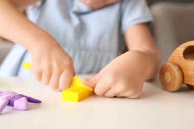 Masada plastikten heykel yapan sevimli küçük kız, yakın plan.