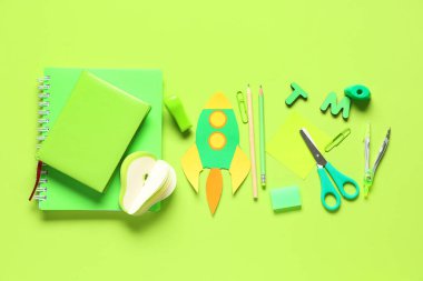 Yeşil arka planda farklı okul kırtasiyesi ve kağıt roketi