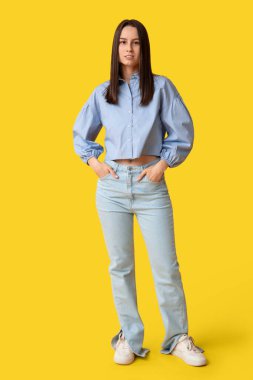 Sarı arka planda şık kotlu güzel bir kadın.