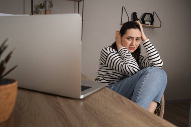 Depresyonda olan genç bir kadın evde, masanın yanında oturuyor.