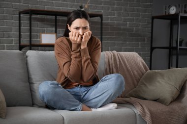 Depresyondaki genç kadın evdeki kanepede ağlıyor.