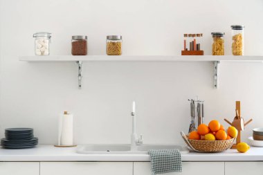 Beyaz stil mutfaktaki tezgahta turuncularla dolu bir sepet.