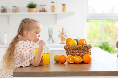 Mutfakta portakal suyu içen tatlı küçük kız.
