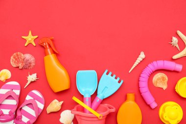 Kırmızı arka plandaki çocuklar için güneş kremi ve plaj aksesuarlarıyla güzel bir kompozisyon