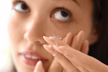 Genç Asyalı kadın evde kontak lens takıyor, yakın plan.