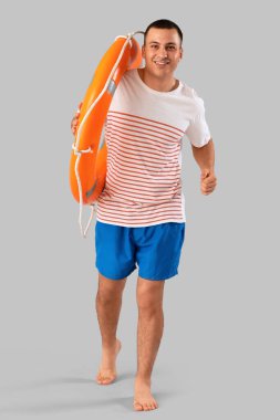 Yüzük şamandırası gri arka planda çalışan mutlu erkek cankurtaran.