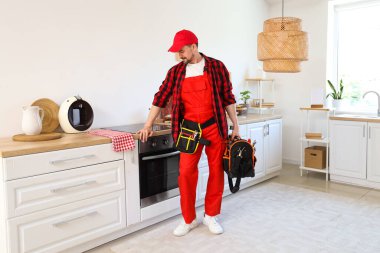 Mutfakta bir çanta alet edevat taşıyan erkek teknisyen.