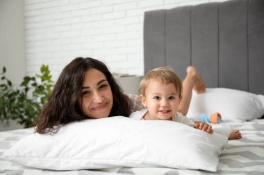 Küçük bebeği ve yastığı evde yatarken mutlu bir anne.