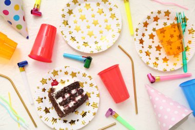 Tek kullanımlık sofra takımı, doğum günü pastası ve ışık arka planında dekor içeren kompozisyon