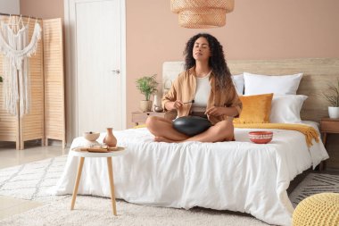 Genç Afro-Amerikalı kadın yatak odasında glukofon çalıyor.