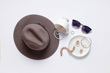 Beyaz arka planda şapka, güneş gözlüğü ve bileziği olan şık aksesuarlar. Üst görünüm