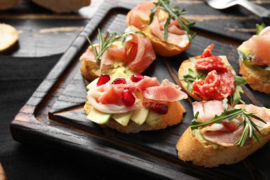 Koyu ahşap arka planda jambonlu lezzetli bruschettalar, yakın plan.