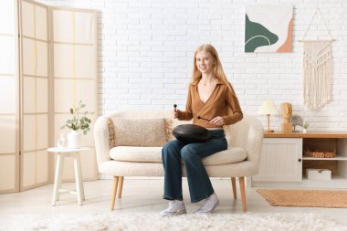 Evdeki kanepede sopayla glukofon çalan güzel genç bir kadın.