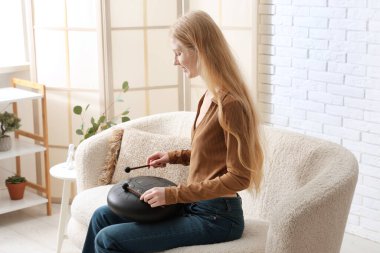 Evdeki kanepede sopayla glukofon çalan güzel genç bir kadın.