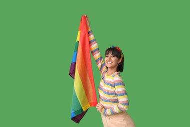 Beautiful young woman with LGBT flag on green background