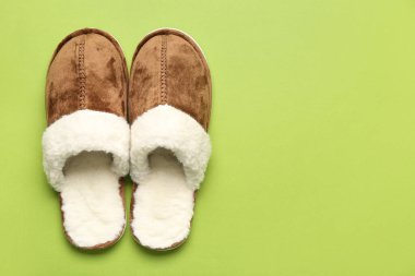 Yeşil arka planda bir çift kahverengi yumuşak terlik. Üst görünüm