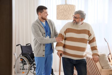 Genç bakıcı evde sopayla kıdemli bir adama bakıyor.