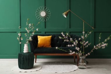 Yeşil kanepe ve çiçekli vazolar şık oturma odasının içinde.