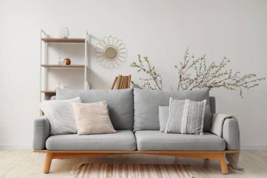 Kanepesi, raf ünitesi ve çiçek açan dalları olan güzel bir oturma odası.