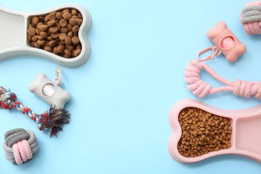 Kemik şeklinde kaseler, kuru yemekler ve mavi arka planda çiğneme oyuncakları.