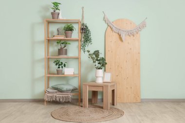 İçinde yeşil bitkiler, raf ünitesi ve masa olan oturma odası.