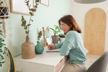 Ofiste okaliptüs dallarıyla yazı yazan genç bir kadın.