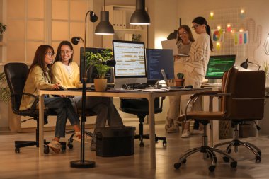 Kadın programcılardan oluşan bir ekip gece ofiste çalışıyor.