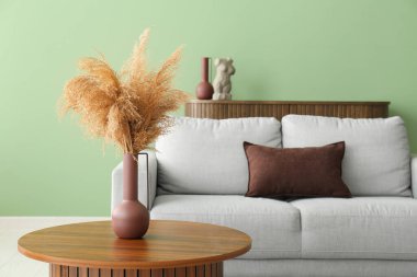 Oturma odasındaki kahve masasında kuru kamışlı vazo.