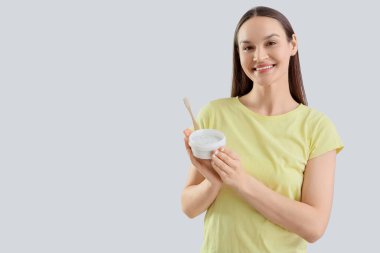 Gülümseyen genç kadın diş pudrası ve hafif arka planda fırçayla