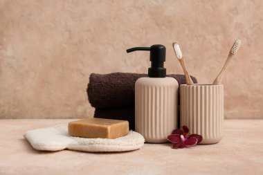 Pembe arkaplanda banyo aksesuarları ve çiçek.