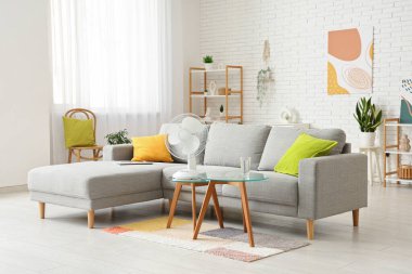 Oturma odasının içinde kahve masasında modern elektrikli vantilatör var.