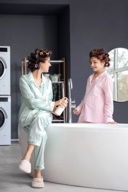 Saç bigudili küçük kız ve annesi evde banyo yapıyorlar.