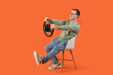 Turuncu arka planda direksiyonu olan mutlu genç adam.