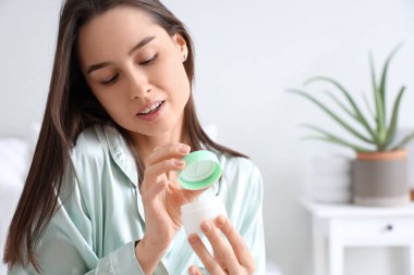 Evinde bir kavanoz aloe vera kremi ile güzel genç bir kadın.