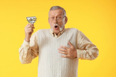 Sarı arka planda kelime WOW ile konuşma balonu tutan yaşlı adam şok oldu