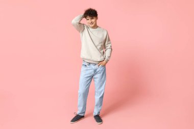 Pembe arka planda şık giyinmiş yakışıklı bir genç.